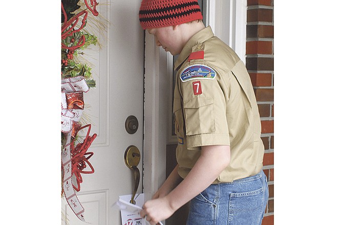 Charles Nelson, a member of Boy Scouts of America Troop 7 in Jefferson City, braves the chilly morning air to place door tags on the west side of Jefferson City, for the "Scouting for Food" program taking place in this area. 