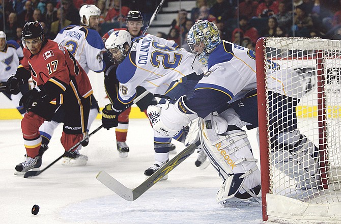 St. Louis Blues goalie Ben Bishop, right, and teammate Carlo Colaiacovo, center, scramble for the puck as Calgary Flames' Rene Bourque tries to get to it first during the first period of an NHL hockey game Sunday, Feb. 27, 2011, in Calgary, Alberta.