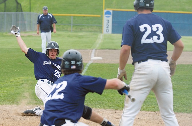 Kyle Henke (22) of the Blue Tigers tells Brian Patrick (25) to slide into home during a game last year against the Oklahoma Panhandle State. At right, is James Johndrow (23) who had just scored. 