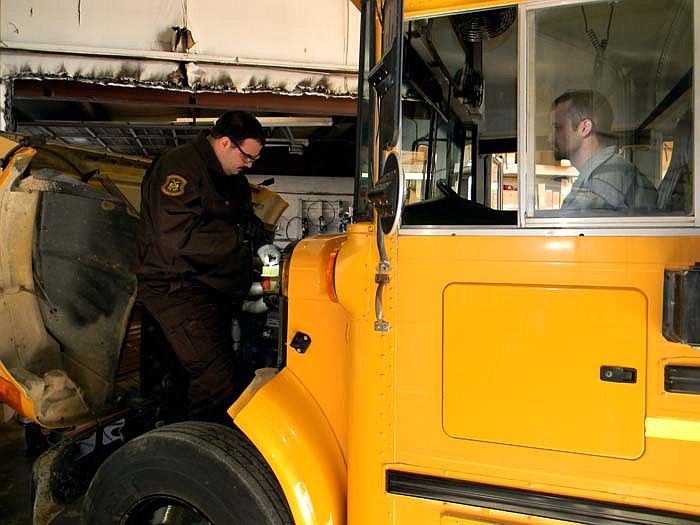 Bryan Potter, right, watches as Bryan Ice, inspector for the Missouri State Highway Patrol, checks the engine during the bus inspections.