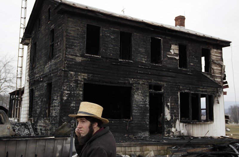 A neighbor stands near the fire-ravaged farmhouse of Theodore and Janelle Clouse on Wednesday in Loysville Pa. Seven Clouse children perished in a fast-moving fire at the home while their mother milked cows.