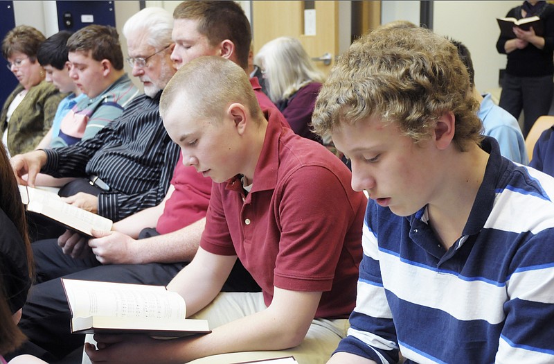 Freshman students Emmett Spradlin, near, and Caleb Propst sing from their hymnals as Pastor Peter Kurowski leads an Ash Wednesday service at Calvary Lutheran High School commons. 