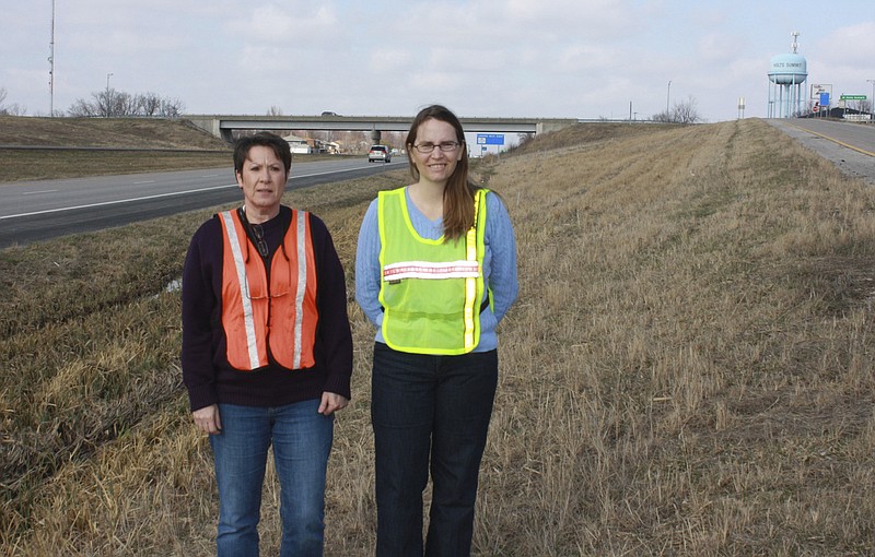 Don Norfleet/FULTON SUN photo: Denise Oxley, right, chairman of the 54 Ramp Beautification Committee, and Pamela Murray, president of the Holts Summit Community Betterment Association, stand at the Southeast Center Street exit ramp in Holts Summit that will be the first of six U.S. 54 exit ramps the organizations will beautify this spring by planting trees and shrubs near the center of the ramp triangle.