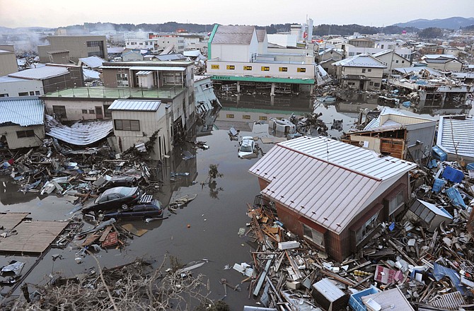 A tsunami-drifted house, bottom right, sits on the debris in Kesennuma, Japan, on Saturday morning after Japan's biggest recorded earthquake slammed into its eastern coast Friday.
