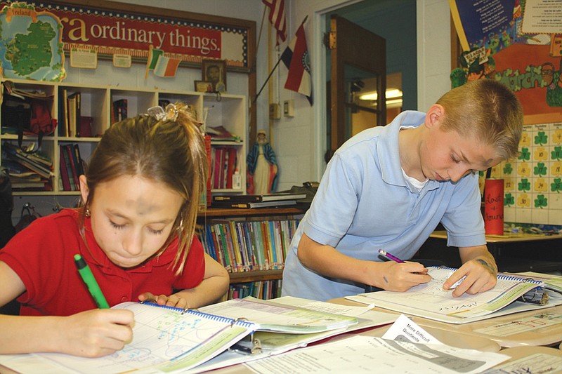 Mandi Steele/FULTON SUN photo: Fourth-graders Kaylee Jennings and A.J. Reid work on their calendars in class after receiving ashes during all-school mass Wednesday morning. According to Fr. Karl Barmann, the tradition on Ash Wednesday of marking the forehead with the sign of the cross in ashes from burning the palms of the previous Palm Sunday is "our sign of pennance and asking for forgiveness of our sins."