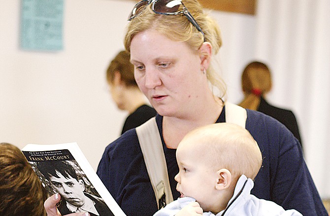 Jennifer Kofahl attends the used book sale at St. Martin's Knights of Columbus with her family Wednesday. Her 10-month-old, Zachary, observed as Jennifer perused the books.