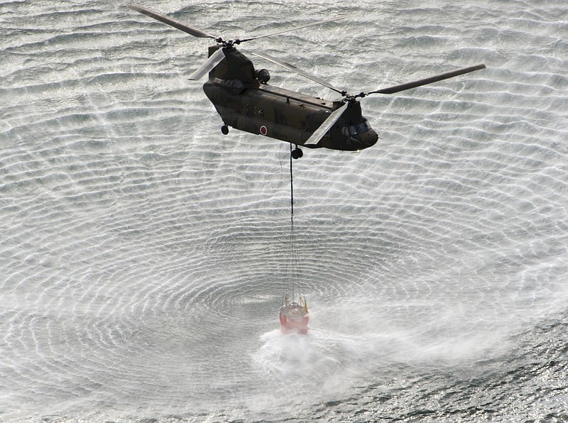 Japan's Self-Defense Forces's helicopter scoops water off Japan's northeast coast on its way to the Fukushima Dai-ichi nuclear power plant in Okumamachi Thursday morning, March 17, 2011. Helicopters are dumping water on a stricken reactor in northeastern Japan to cool overheated fuel rods inside the core. (AP Photo/Yomiuri Shimbun, Kenji Shimizu)