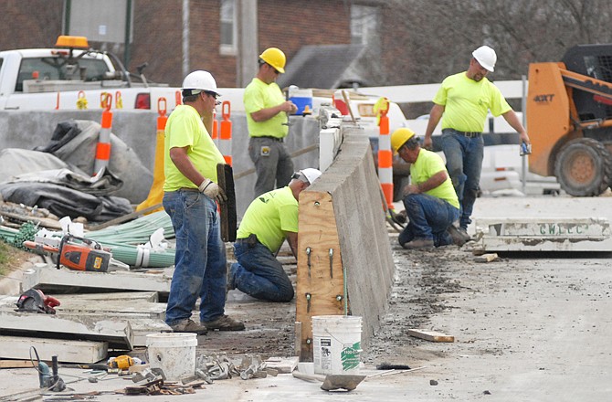 Aplex workers work on a concrete barrier at the West Main Street entrance of what will soon be the new pedestrian/bike bridge located on the northbound of the Missouri River bridge.