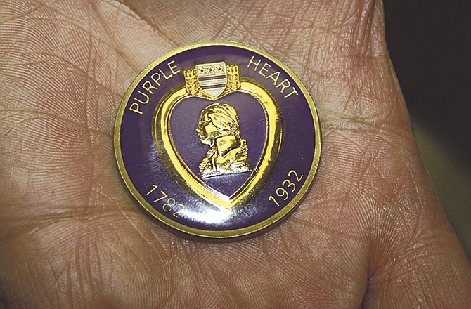 In this March 16, 2011 photo, Sierra Vista resident Al Lee, holds the Purple Heart coin he received, along with the Purple Heart Medal and lapel pin, after being wounded in Iraqi in 2003, in Tucson, Ariz. The commander of the local chapter of the Military Order of the Purple Heart presented the coin to Rep. Gabrielle Giffords' staff on Wednesday for them to give to the congresswoman who was shot in the head on Jan. 8 in Tucson. (AP Photo/Provided by Congresswoman Giffords' office via Sierra Vista Herald)