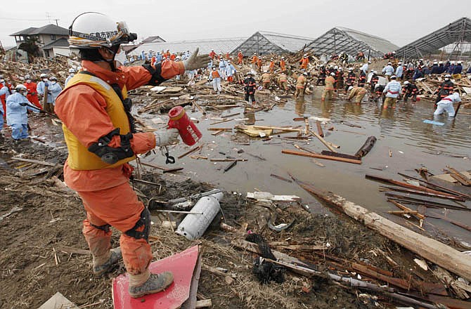 Rescuers sift through the remains of a property in the suburb of Natori, Miyagi Prefecture, Japan, Sunday, March 20, 2011 after the March 11 earthquake and tsunami devastated the area.