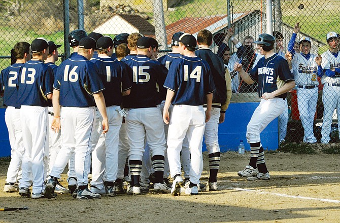 Zach Rockers is greeted at home plate by his Helias teammates after hitting a three-run home run in the top of the third inning of Monday's game against Fatima at Lions Field in Westphalia.