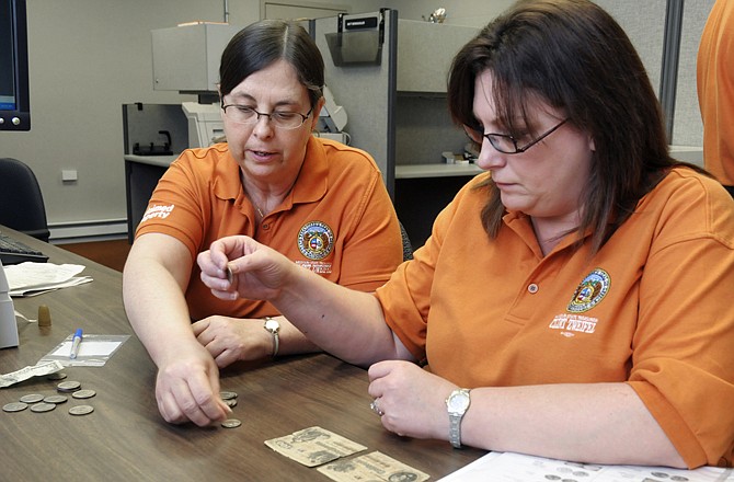 Tammy Pettit, right, and Nancy Tennison review items, coins and cash found in safe deposit boxes as they catalog the items for easy reference.