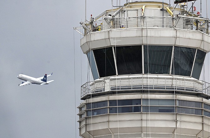 A passenger jet flies past the FAA control tower Thursday at Washington's Ronald Reagan National Airport. A control tower supervisor who was asleep while two airliners landed at the airport this week has been suspended.