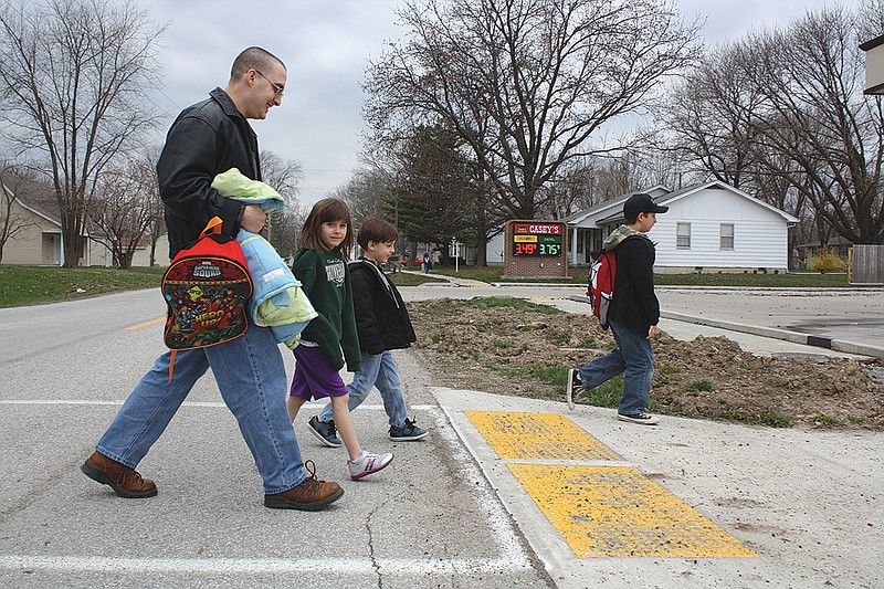 Mandi Steele/FULTON SUN photo: Brian Simpson uses the crosswalk to help his son, Drake, and Katherine Menard cross Route E after school Wednesday. The crosswalk is near Auxvasse Elementary School and students use it daily to walk to and from the school.