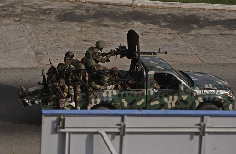 Unidentified troops drive past in the city of Abidjan, Ivory Coast, Friday, April 1, 2011.Heavy fighting raged Friday near Ivory Coast's presidential palace and mansion and the state TV broadcaster as armed forces loyal to the elected leader tried to install him to power and oust the country's strongman.