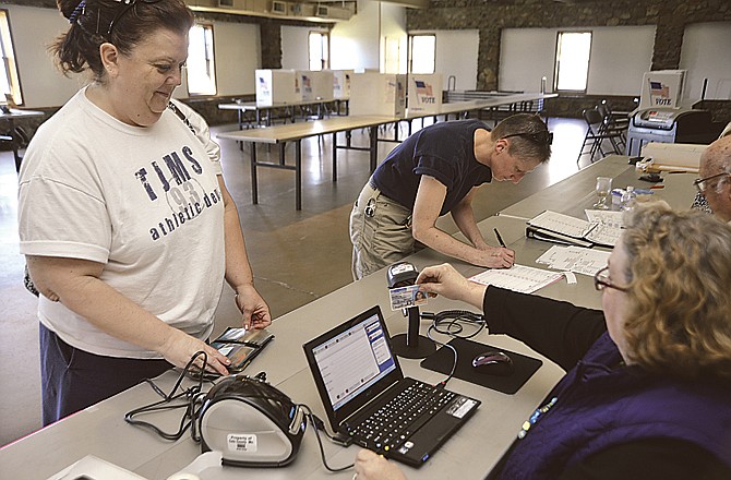 Poll worker Sarah Briggs, right, scans Margaret Gale-Wells' driver's license through a new Election Administrators system Tuesday afternoon at Jefferson City's McClung Park pavilion. "We're moving voters through fast because we don't have to look them up in the book," Briggs said, adding the new system will make an even bigger difference in major elections. Briggs can also access the system with a voter's name, date of birth, voter card or voter ID. The information appears on the computer screen for verification. 