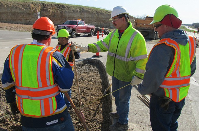 Missouri Department of Transportation workers, from left, Rich Murray, Pancho Bejarano, Bob Houchins and Pat Wulff work to pave an area where Lookout Drive crosses U.S. 50 West in Cole County.