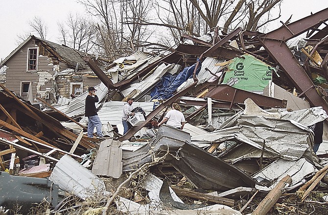 Jason Mauch, center, carries a basket of belonging from his destroyed house in Mapleton, Iowa, Sunday, April 10, 2011, after a large tornado struck the town. Authorities reported no serious injuries.