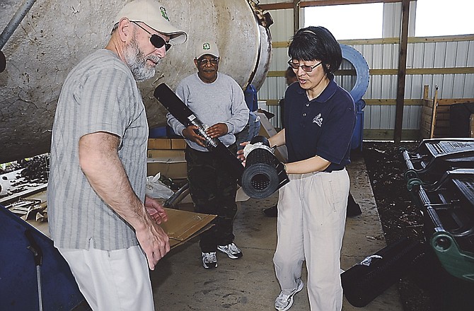 Cooperative Extension associate professor Hwei-Yiing Johnson, right, distributes portable compost bins after a seminar Saturday morning at Lincoln University's Alan T. Busby Farm Compositing Facility. The large tank at left is used to compost food waste from the university campus.