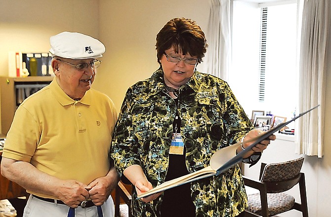 Helen Rigdon looks at one of the books Jack Glaven of the Jefferson City Kiwanis Club has in club's collection. The club will be placing the 90-year-old collection in the library's keeping, where it will be available as reference material.
