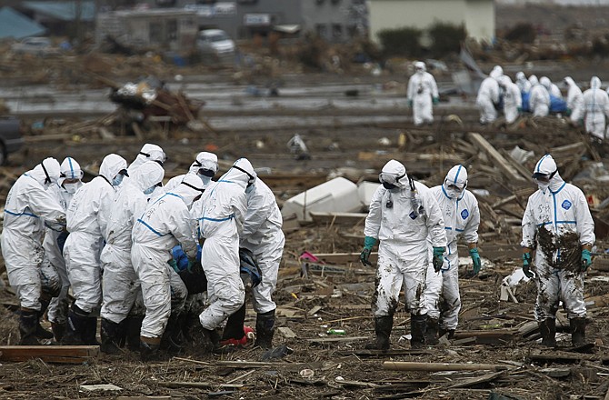 Japanese police officers wearing protective suits carry victims Friday while searching for missing people in Minami Soma, Fukushima Prefecture, northeastern Japan. The goverment on Tuesday ranked it's nuclear crisis at the highest possible severity on an international scale.