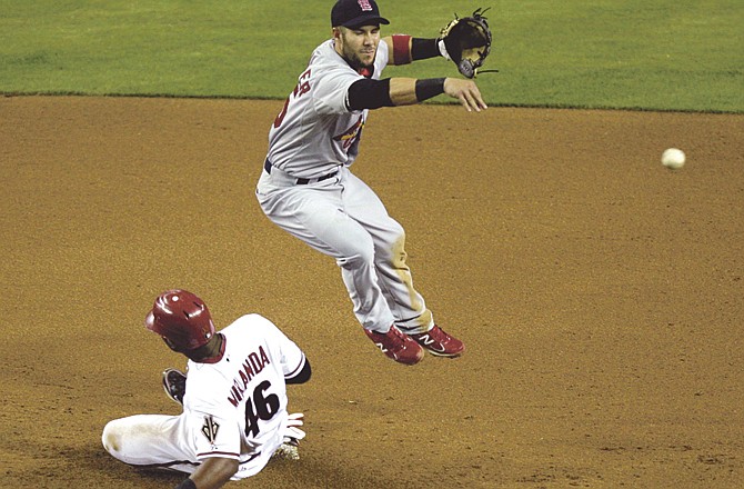 St. Louis Cardinals second baseman Skip Schumaker, top, leaps to avoid the slide by Arizona Diamondbacks' Juan Miranda, bottom, as he throws to first to turn a double play on a ball hit by Barry Enright in the fourth inning of a baseball game Monday, April 11, 2011, in Phoenix.