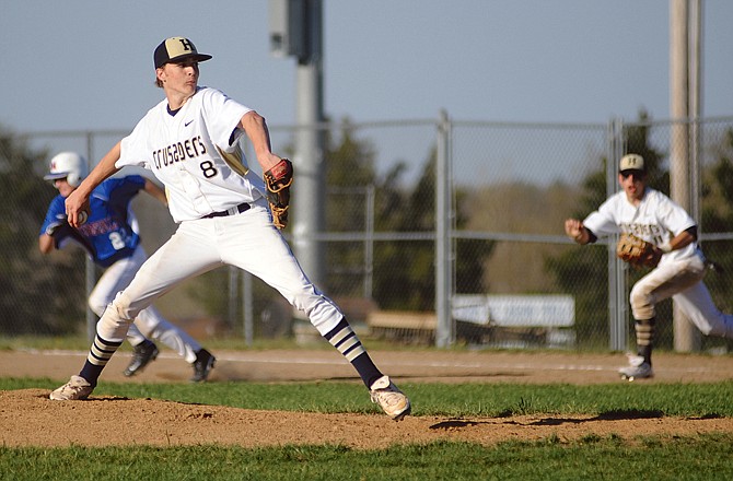 Helias pitcher Deion Hughes goes to the plate as Moberly's Audi Weis (background) breaks for second during Tuesday's game at the American Legion Post 5 Sports Complex.