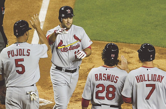 St. Louis Cardinals' Lance Berkman, top, gets high-fives from teammates Albert Pujols (5), Colby Rasmus (28) and Matt Holliday (7) after hitting a grand slam against the Arizona Diamondbacks in the second inning of an MLB baseball game on Wednesday, April 13, 2011, in Phoenix.