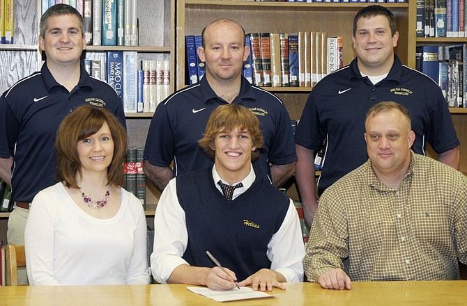 Ty Loethen of Helias (seated center) signs a letter of intent Wednesday morning to wrestle at Northern Illinois University in DeKalb, Ill. Also seated are his parents Angela and Ryan Loethen. Standing (from left) are Helias assistant coach Tyler Brown, head coach Travis Reinsch and assistant coach Jeff Pickering.