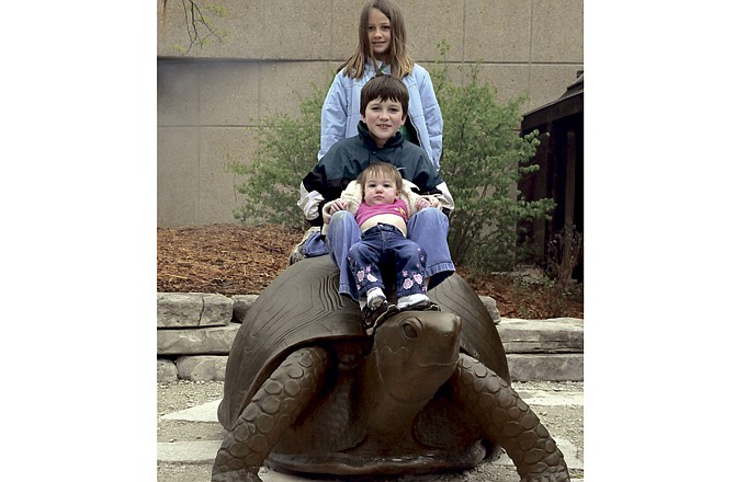 Ireland Sczepanski, 10 months, sits with Benjamin, 7, and Kennady Rowe, 8, atop the newest sculpture at the Runge Nature Center. 