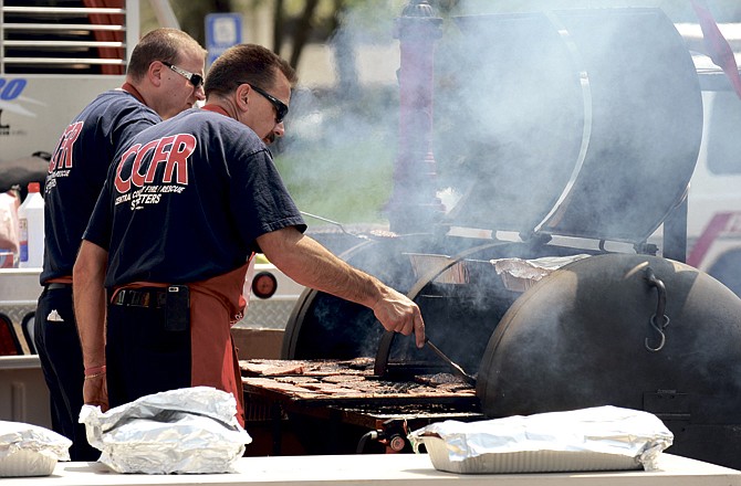 Steve Brown, near, and James Smoot grill hamburgers Tuesday for the annual Firefighter and EMS Day at the Missouri Capitol. They are with Central County Fire Rescue in St. Peters, Mo.