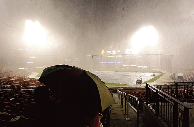 Dan Rothe, right, huddles under an umbrella with his wife, Cheryl, as torrential rain falls before a baseball game between the St. Louis Cardinals and the Washington Nationals on Tuesday, April 19, 2011, in St. Louis.