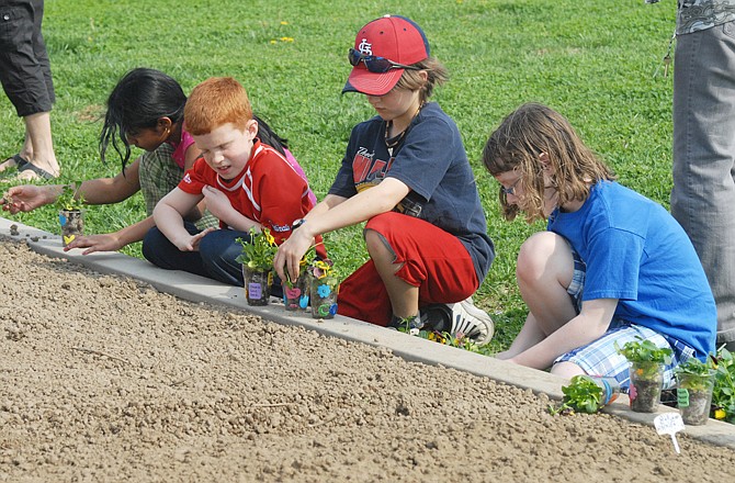 A group of West School third- through fifth-graders plants pansies that they will bring to Heisinger Home next week.