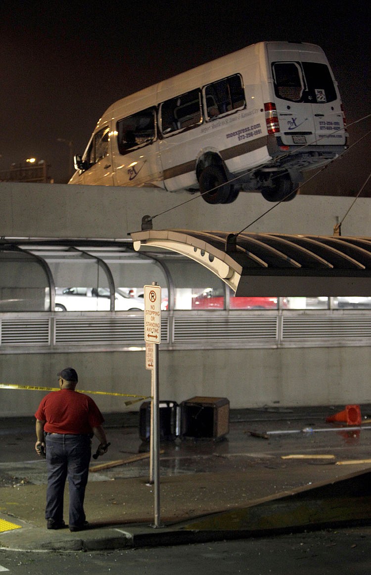 A van hangs over the side of a parking garage at Lambert St. Louis International Airport Friday, April 22, 2011, in St. Louis. Several people at the airport were injured Friday after an apparent tornado touched down, spewing debris over the airfield, bursting glass in the concourse and damaging cars atop a parking garage.