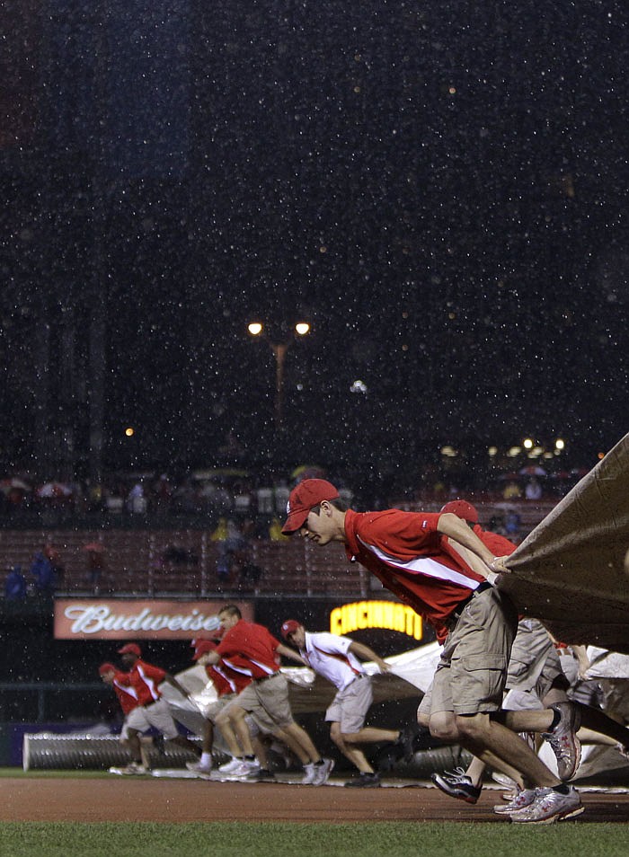 Members of the Busch Stadium grounds crew pull a tarp over the infield at the start of a rain delay during the first inning of a baseball game between the St. Louis Cardinals and the Cincinnati Reds, Friday, April 22, 2011, in St. Louis.