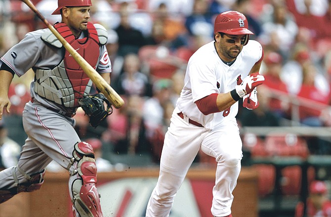 St. Louis Cardinals' Nick Punto, right, heads for first after laying down a sacrifice bunt as Cincinnati Reds catcher Ramon Hernandez, left, runs for the ball in the seventh inning of a baseball game, Saturday, April 23, 2011, in St. Louis. The Reds defeated the Cardinals 5-3. 