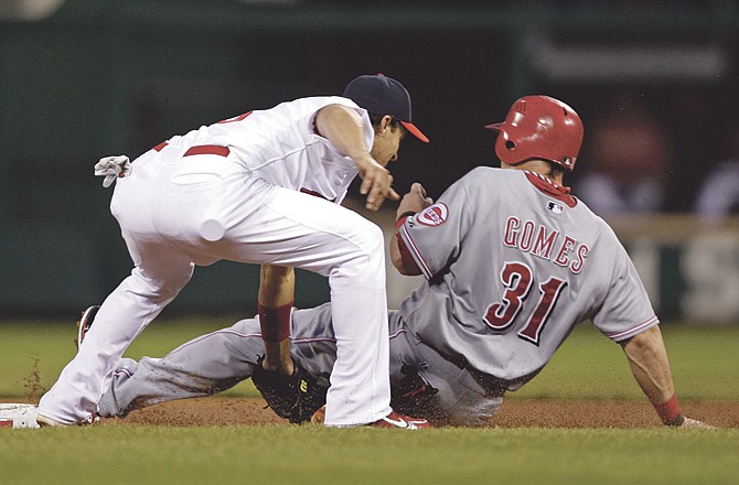 
Cardinals shortstop Ryan Theriot tags out the Reds' Jonny Gomes on a steal attempt during the second inning of Sunday night's game in St. Louis.

