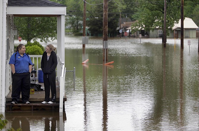 Kasey Medley, right, stands on the front porch of her flooded home with her friend Erica Cass in Poplar Bluff.