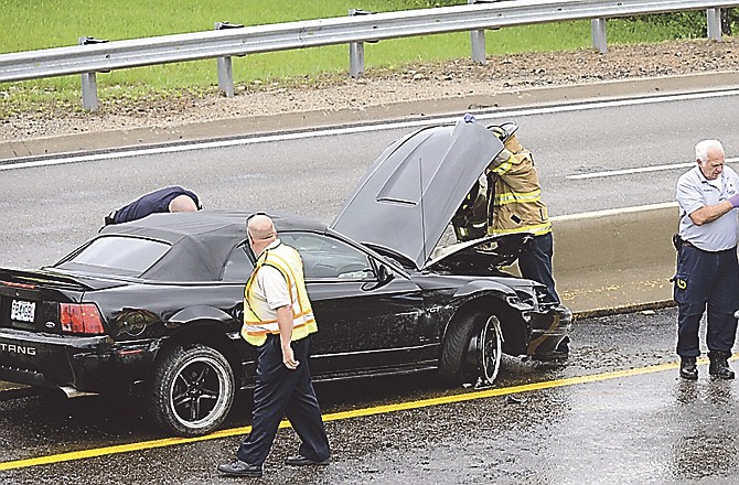 Emergency personnel respond to a vehicle that crashed into the concrete median Monday afternoon. The driver, who was out and being assisted when this photo was taken, received moderate injuries, police reported.