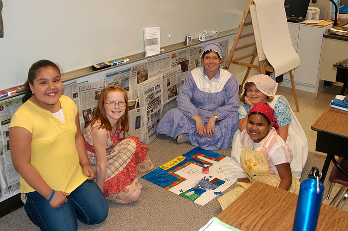 Fourth Grade Teacher Randi Schwartz, center, joins some of the students at the Pioneer Day game board.