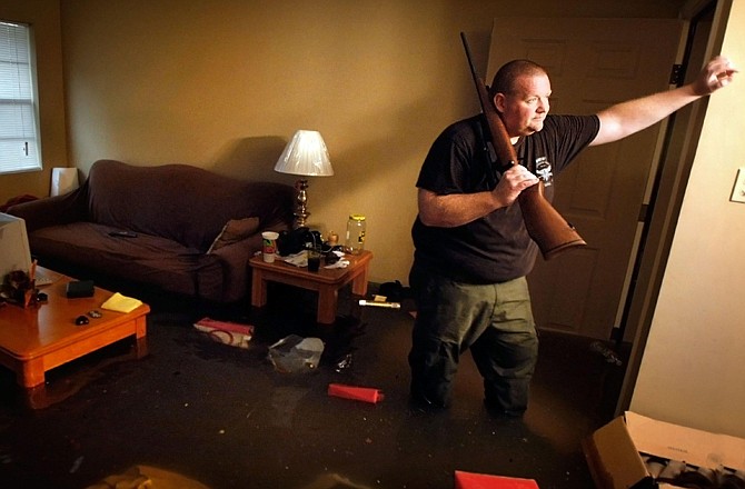 Knee deep in flood water, Crittenden County, Ark., Deputy Darryn Richardson wades through his apartment to retrieve his hunting rifles Wednesday in West Memphis, Ark., where most of the ground-floor units were flooded by storm runoff. West Memphis was declared a disaster area by the state as rains continued to pound the mid-south.