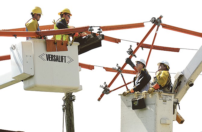 Nathan Hill, at left, and Tyler Headrick remove overhead power lines from the pole as Clint Underwood, front, and Charles Stump, in bucket at right, support the training facility lines using a fiberglass tree. Hill works for United Electric in Savannah; Headrick for Howell-Oregon; Underwood for N.W. Electric Power; and Stump works for Osage Valley Cooperative in Butler. They were training in Jefferson City to change out a three-phase pole. 