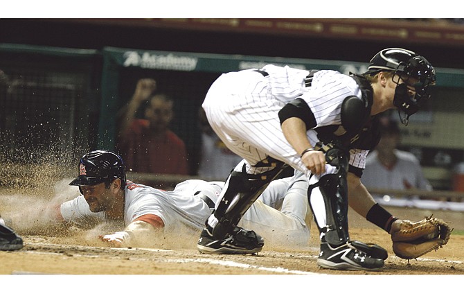 St. Louis Cardinals' Nick Punto, left, gets a face full of dirt while sliding safely across home plate as Houston Astros catcher J.R. Towles makes the catch in the seventh inning of a baseball game Wednesday, April 27, 2011, in Houston. Punto scored from second base on an Albert Pujols single. 