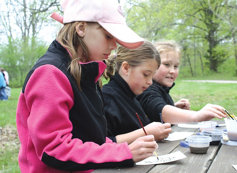 Mandi Steele/FULTON SUN photo: Mattie Hampton, fourth-grader at Bush Elementary School, uses paint made out of soil to color a picture at the Paint with Soil Station. Twelve stations were set up at Prairie Fork Conservation Area on Wednesday for an Earth Day event for area students. 
