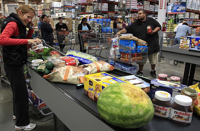 Costco shoppers load the conveyer belt at the checkout counter at Costco in Mountain View, Calif. Americans saw their incomes rise in March, which spurred spending.