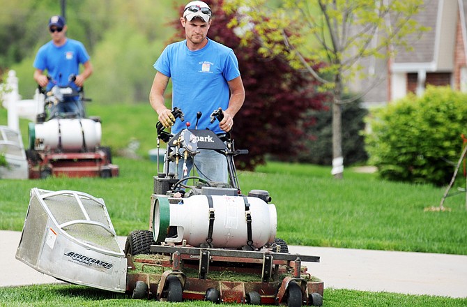 Josh Limbach, foreground, and Andrew Fritz operate walk-behind mowers that have been converted to propane fuel. They were part of a larger crew working on the city's West side. All-Seasons Landscaping has converted their fleet of lawn mowers to propane.