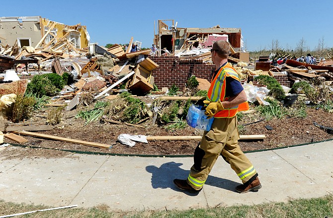 Oak Grove-Thatch volunteer firefighter Josh Adams brings a case of water to people working on a ruined home in the destroyed East Limestone communities near Athens, Ala. The neighborhood was destroyed by Wednesday's tornado.