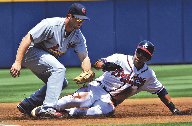 St. Louis Cardinals third baseman David Freese, left, tags out Atlanta Braves' Martin Prado sliding on a fielder's choice that was fielded by shortstop Tyler Greene hit by Braves batter Jason Heyward during the first inning of a baseball game, Saturday, April 30, 2011, in Atlanta.