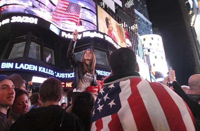 Draped in the American flag, Pedro Valerio, of Elizabeth, N.J., right, and others in New York's Times Square react to the news of Osama Bin Laden's death early Monday morning May 2, 2011. 