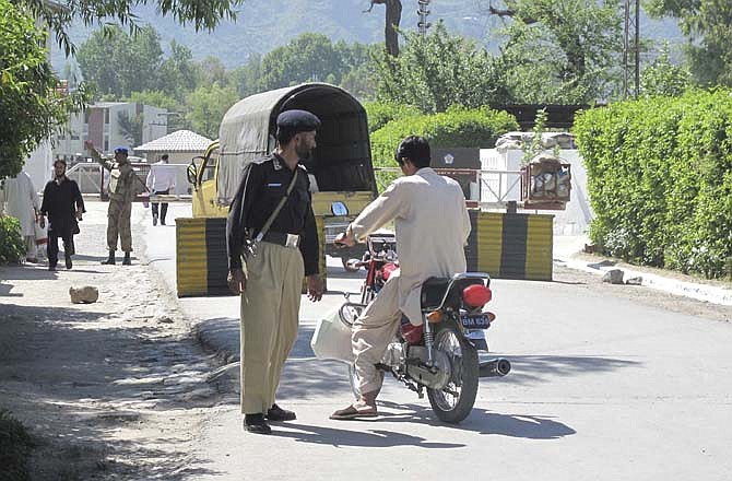 A Pakistani police officer talks to a motor cyclist at a security check post in Abbottabad, Pakistani on Monday, May 2, 2011. Osama bin Laden was holed up in a two-story house 100 yards from a Pakistani military academy in Abbottabad when four helicopters carrying U.S. anti-terror forces swooped in the early morning hours of Monday and killed him.